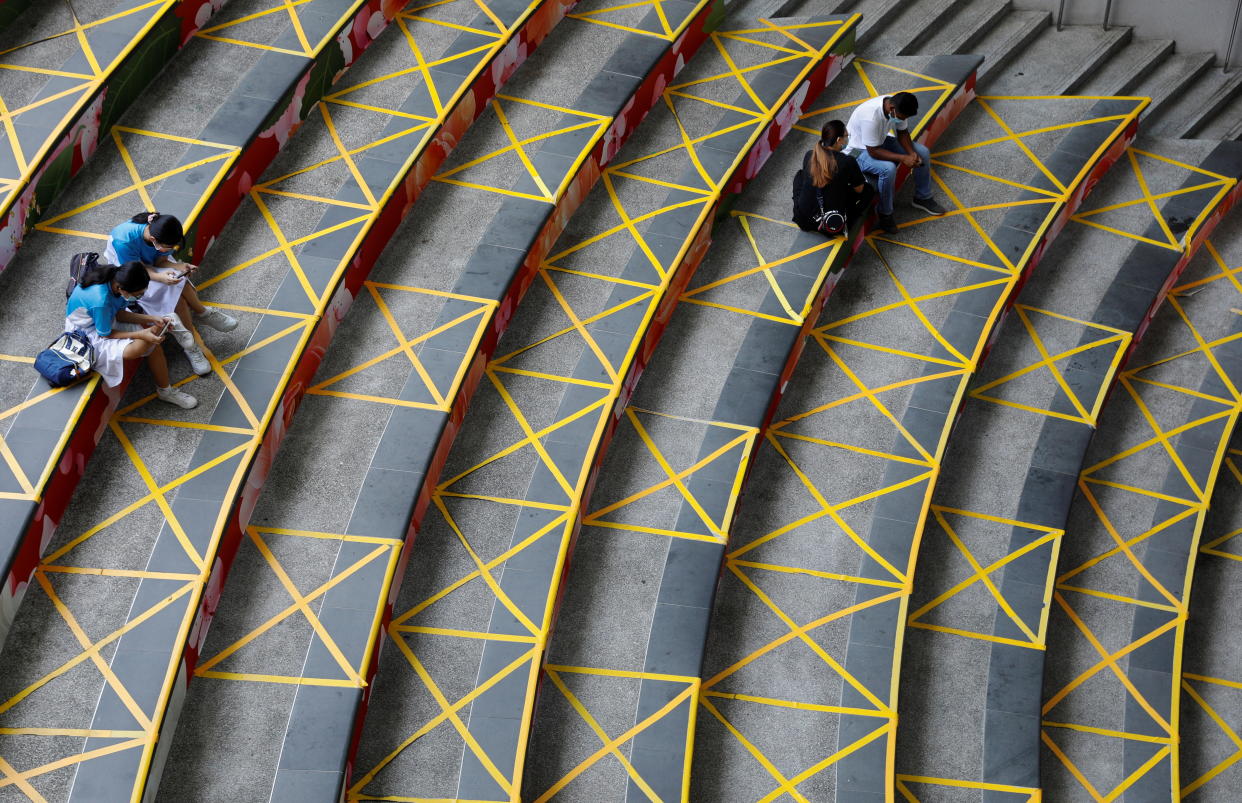 People sit next to social distancing stickers that demarcate the public seating areas of a mall, amid the coronavirus disease (COVID-19) pandemic, in Singapore October 6, 2021. REUTERS/Edgar Su