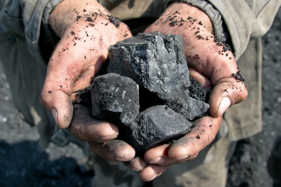 A miner holding chunks of coal in his hands.