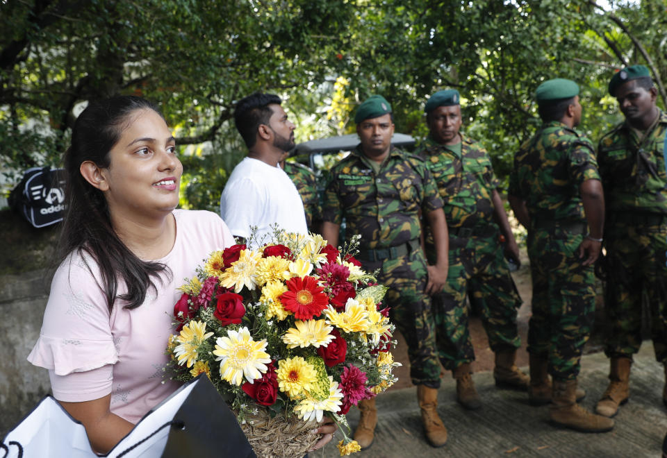 A supporter waits with flowers outside the residence of Sri Lanka's former defense secretary and presidential candidate Gotabaya Rajapaksa in Colombo, Sri Lanka, Sunday, Nov.17, 2019. Sri Lanka’s ruling party presidential candidate conceded defeat on Sunday to Rajapaksa, marking the return of a family revered by the Sinhalese Buddhist majority for the victory over the Tamil Tiger rebels but feared by Tamil and Muslim minorities. (AP Photo/Eranga Jayawardena)