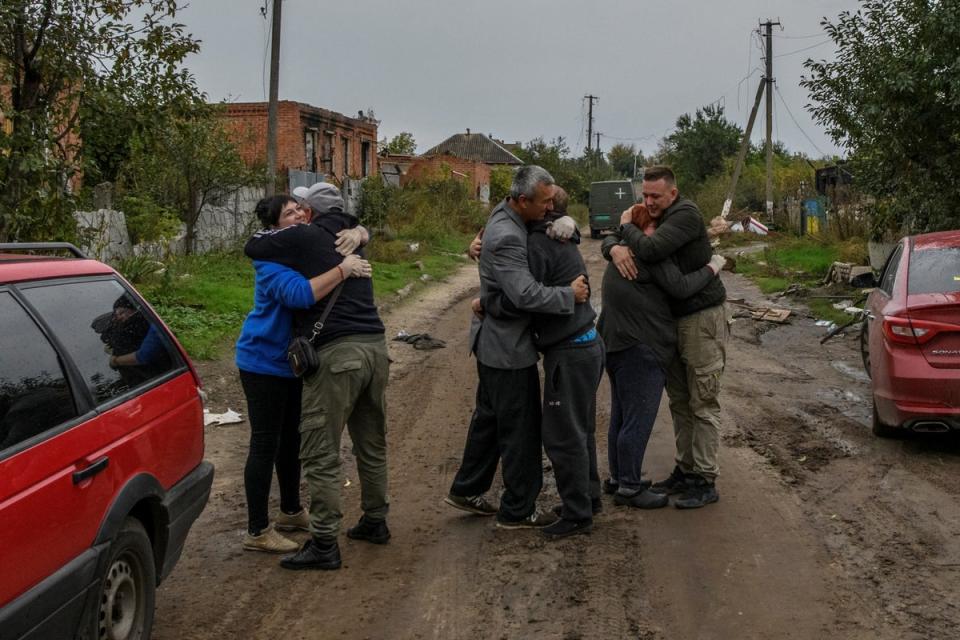 Neighbours embrace after they return from evacuation to the liberated village of Kamianka in the Kharkiv region on Sunday (Reuters)