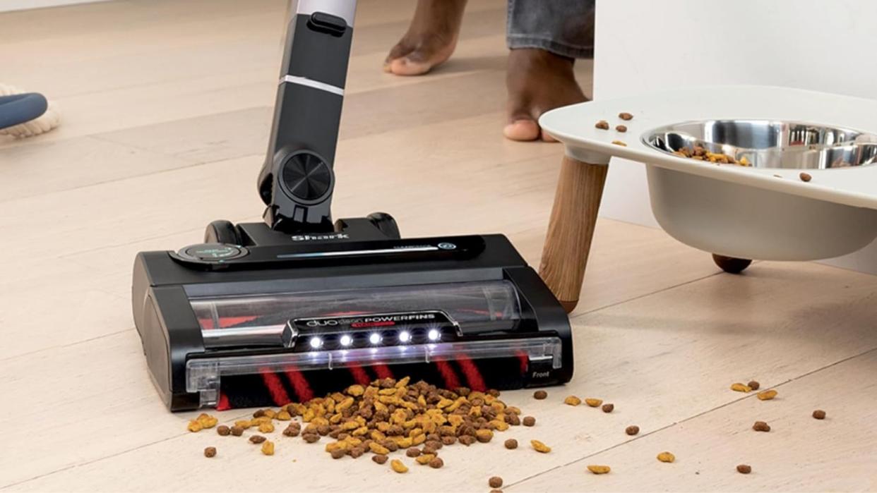  An example of what's on sale in the Shark Black Friday sales, a Shark Stratos Cordless Vacuum vacuuming kibble in front of a pet food bowl. 