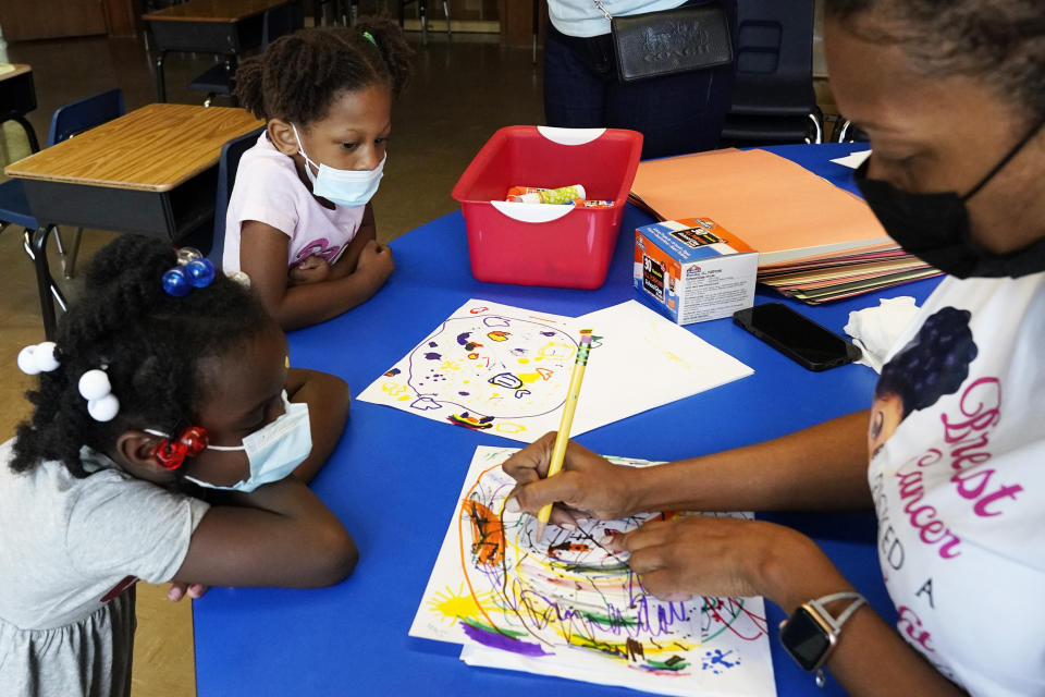 Laiah Collins, 4, top left, and Charisma Edwards, 5, work with Davetra Richardson (STLS), right, in a classroom at Chalmers Elementary school in Chicago, Wednesday, July 13, 2022. America's big cities are seeing their schools shrink, with more and more of their schools serving small numbers of students. Those small schools are expensive to run and often still can't offer everything students need (now more than ever), like nurses and music programs. Chicago and New York City are among the places that have spent COVID relief money to keep schools open, prioritizing stability for students and families. But that has come with tradeoffs. And as federal funds dry up and enrollment falls, it may not be enough to prevent districts from closing schools. (AP Photo/Nam Y. Huh)