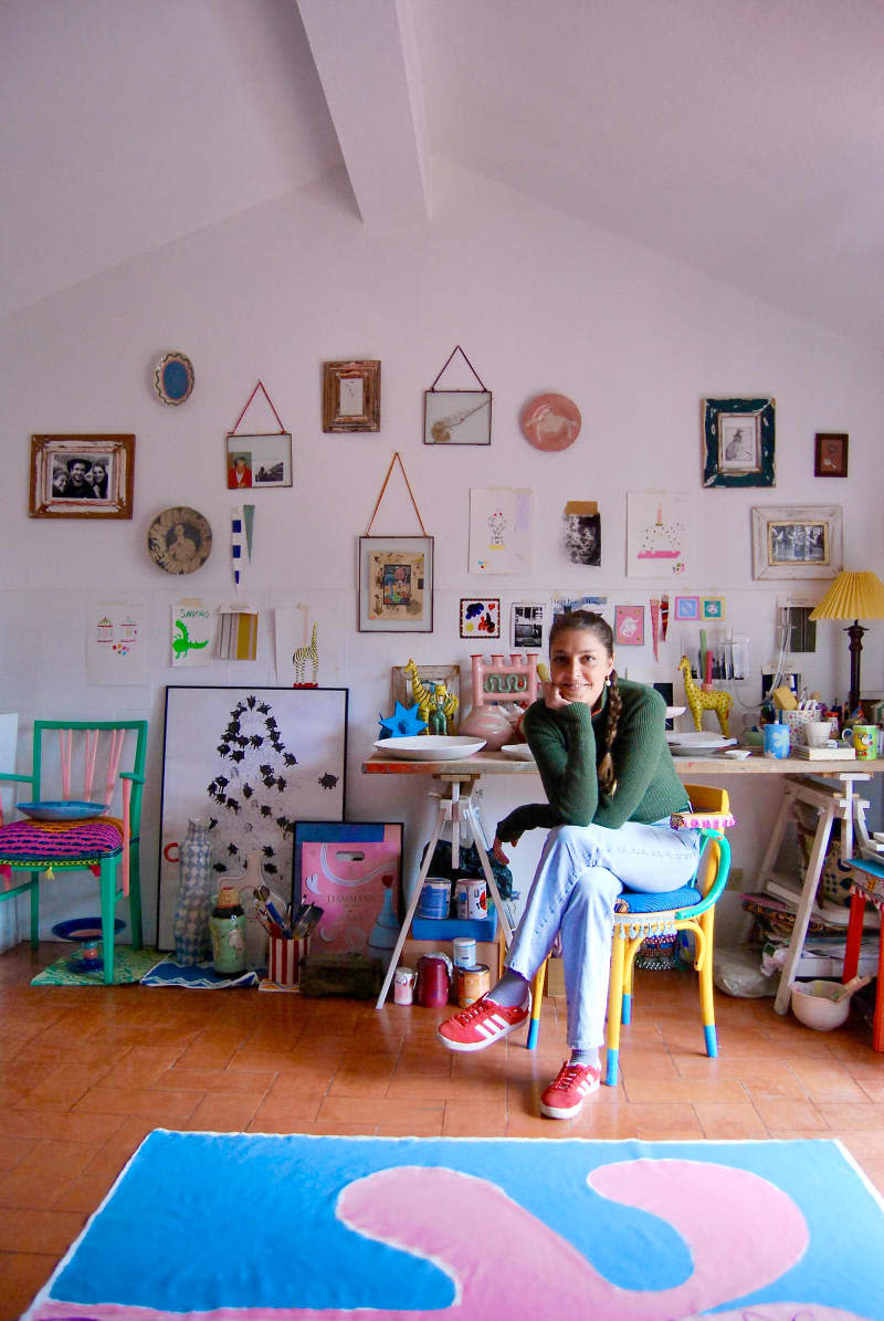 Dweller sits at desk in front of gallery wall in room with blue and pink rug.