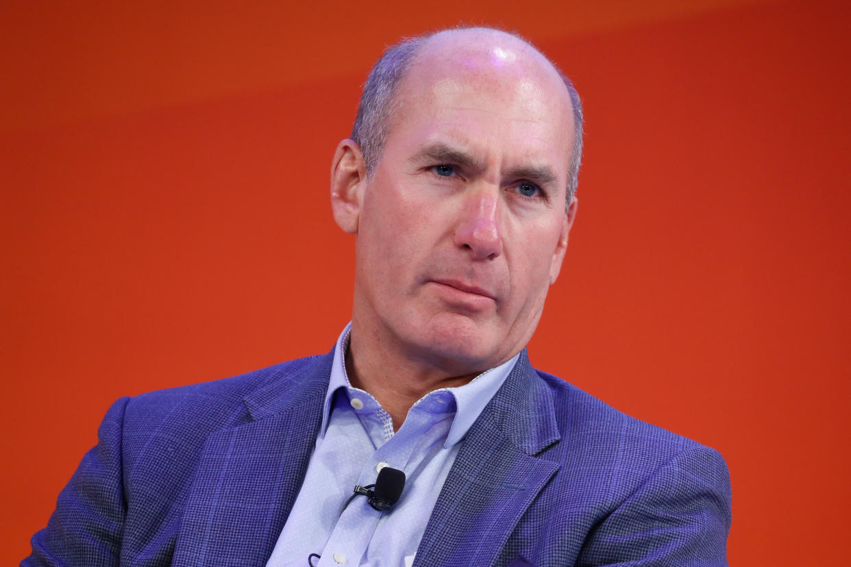 AT&T CEO John Stankey is pictured against a red backdrop.