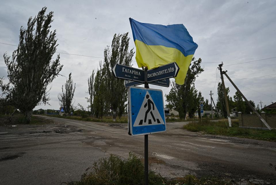 A Ukrainian flag waves on a street of a recently liberated Ukrainian village.