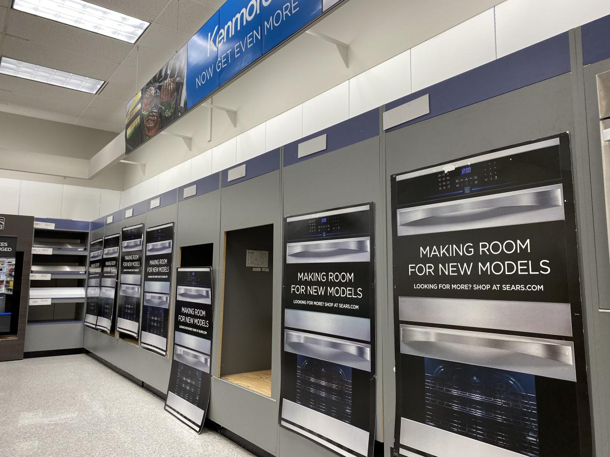 Cardboard signs saying "Making room for new models" covering up empty shelves at Sears Kenmore