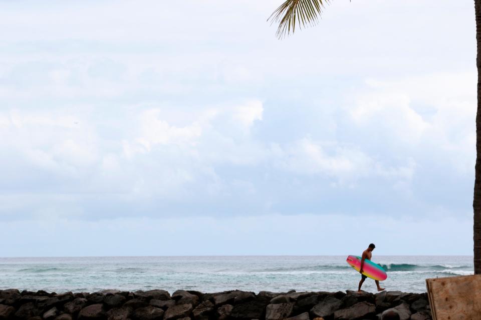 In this April 21, 2020, photo, a surfer returns to Waikiki Beach in Honolulu.