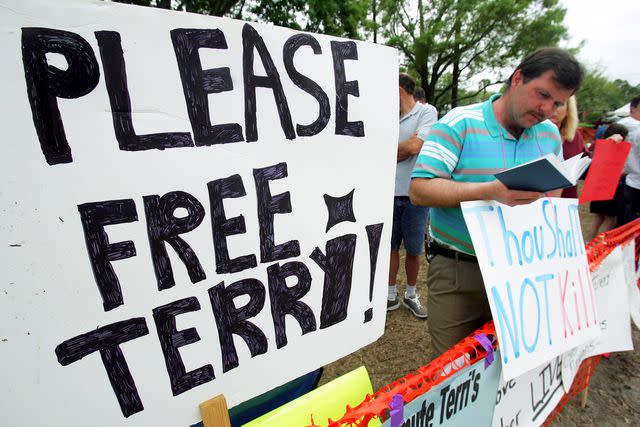 <p>Craig Warga/NY Daily News Archive via Getty</p> March 24, 2005: Paul Reese of Carlisle, Pa., reads the Bible as he and other pro-life protesters stand vigil outside the Woodside Hospice in Pinellas Park, Fla., where Terri Schiavo's feeding tube was removed on March 18. A state judge and the U.S. Supreme Court refused to intervene in her case today, leaving the severely brain-damaged woman's parents with only the slimmest hopes in their fight to keep her alive.