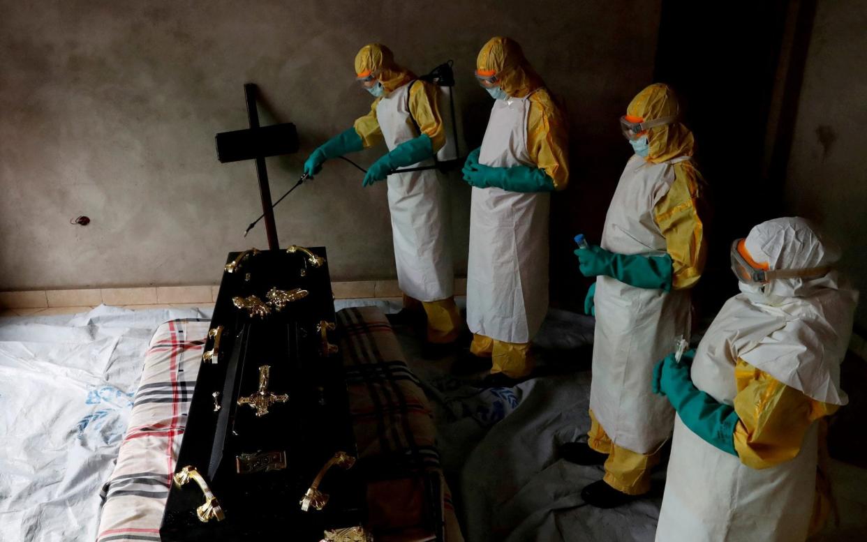 A healthcare worker sprays a room during the funeral of an Ebola victim - REUTERS