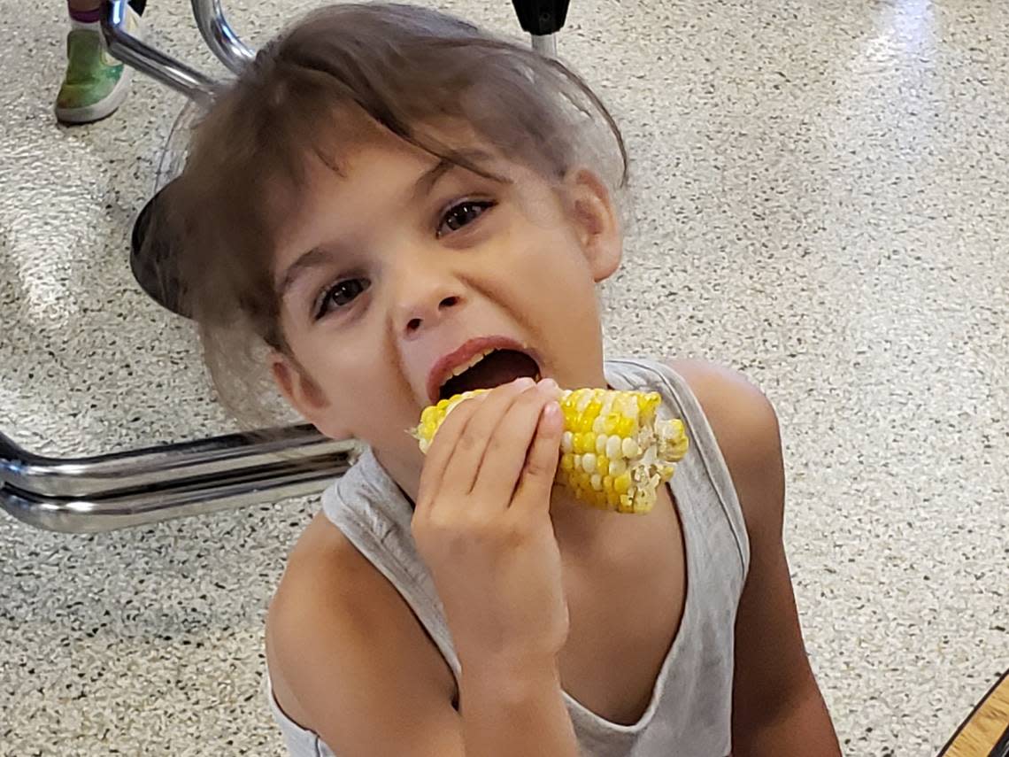 Lyra Crane enjoys an ear of corn at Pleasant Lea Elementary.