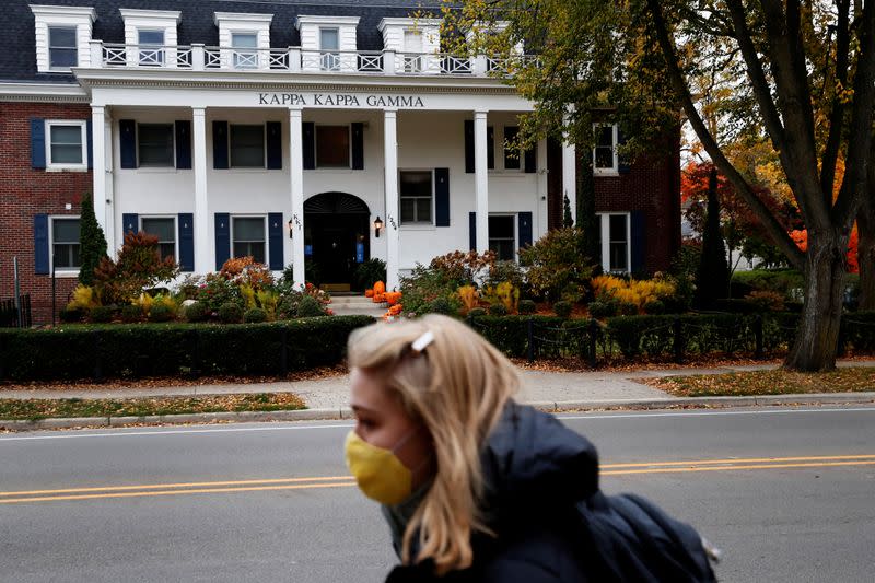 FILE PHOTO: A woman wearing a protective face mask walks past a sorority house on the University of Michigan campus in Ann Arbor