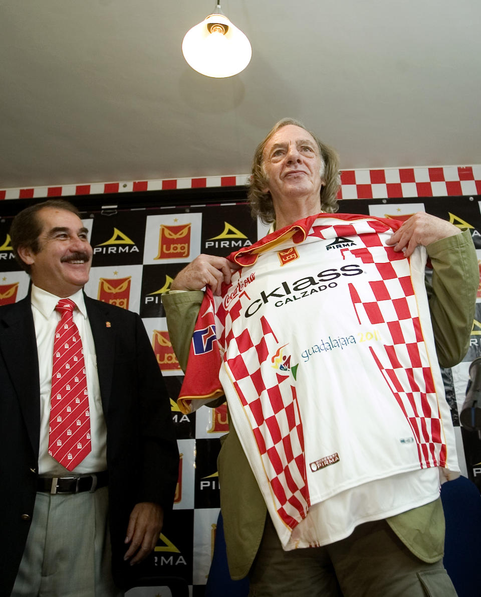 FILE - Argentinean coach Cesar Luis Menotti , right, holds up a Tecos jersey to the media during his official presentation as its new head-coach in Guadalajara, Mexico, Wednesday Aug. 29, 2007. Menotti, the charismatic coach who led Argentina to its first World Cup title in 1978, has died, the Argentine Football Association said Sunday, May 5, 2024. He was 85. (AP Photo/Guillermo Arias, File)
