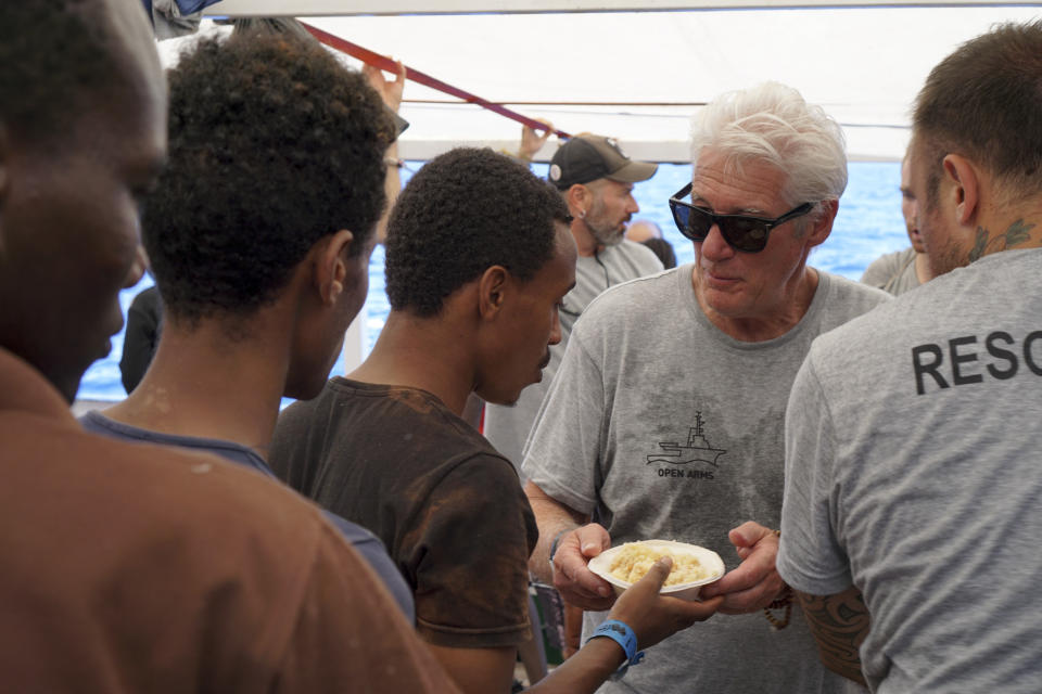 Actor Richard Gere, right, helps serving meals to migrants aboard the Open Arms Spanish humanitarian boat as it cruises in the Mediterranean Sea, Friday, Aug. 9, 2019. Open Arms has been carrying 121 migrants for a week in the central Mediterranean awaiting a safe port to dock, after it was denied entry by Italy and Malta. (AP Photo/Francisco Gentico)