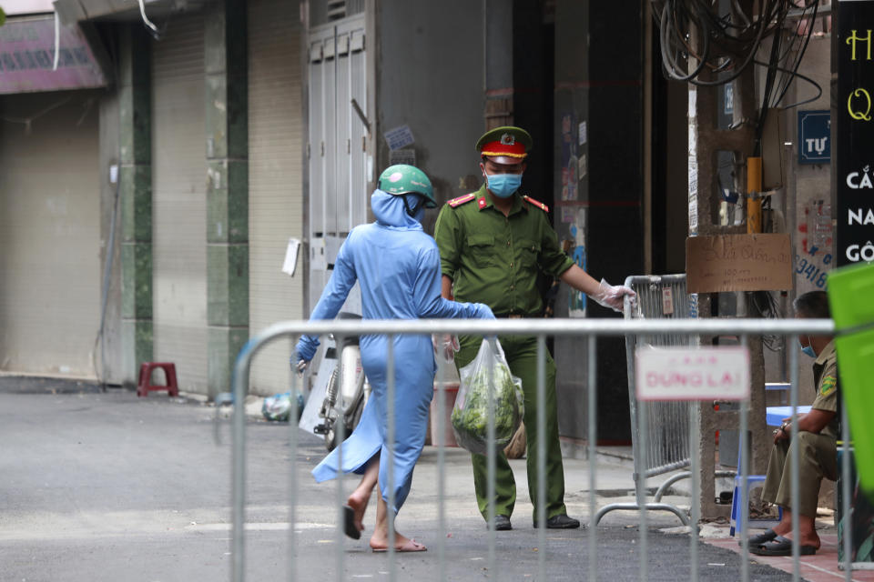 A woman leaves the food shopping for her relatives at the barricaded entrance to the residence of a confirmed COVID-19 case in Hanoi, Vietnam on Wednesday, July 29, 2020. Vietnam intensifies protective measures as the number of locally transmissions, starting at a hospital in the popular beach city of Da Nang, keeps increasing since the weekend. (AP Photo/Hau Dinh)