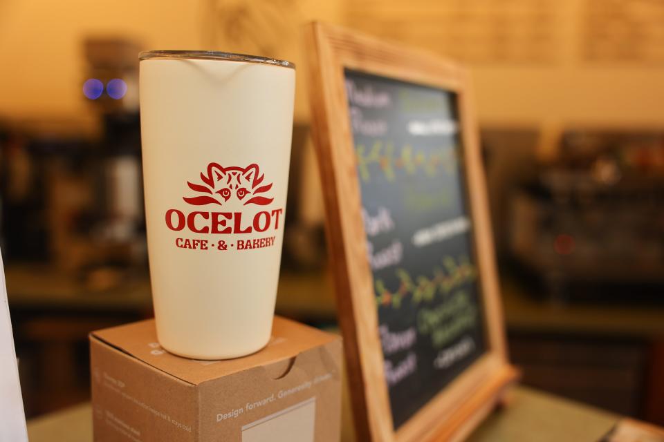 A travel coffee cup sits adorned with the logo of Liz Post and Jason Smith’s newly opened Ocelot Cafe and Bakery.