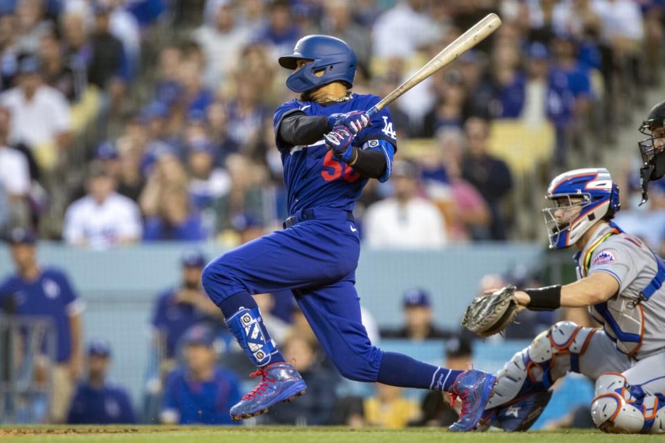 The Dodgers' Mookie Betts hits a three-run double in the second inning while Mets catcher Patrick Mazeika looks on.