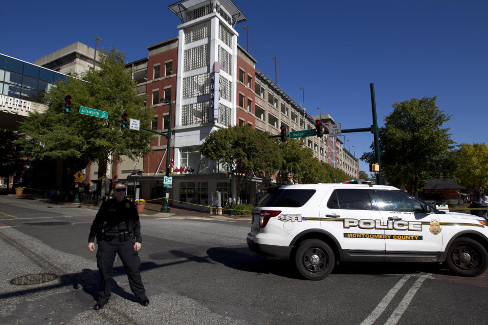 Montgomery police officer block the intersection where a parking garage is seen, where a police officer was shot, in downtown Silver Spring, Md., Monday, Oct. 14, 2019. Police in Montgomery County, Maryland, said they were searching for at least one person after an officer was found shot in a parking garage in downtown Silver Spring on Monday. (AP Photo/Jose Luis Magana)
