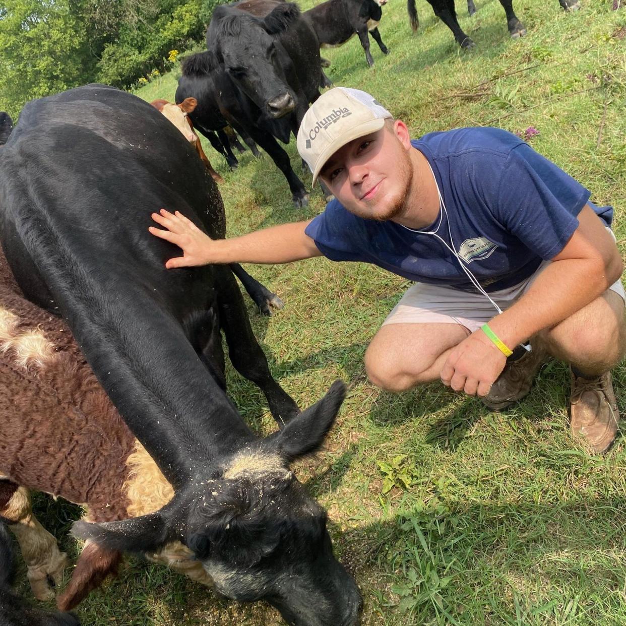 Will Warner, 22, squats down and pets a cow in this undated photo.