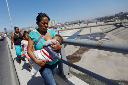 Members of a migrant caravan from Central America walk on a bridge at the end of their caravan journey through Mexico, prior to preparations for an asylum request in the U.S., in Tijuana, Baja California state, Mexico April 27, 2018. REUTERS/Edgard Garrido