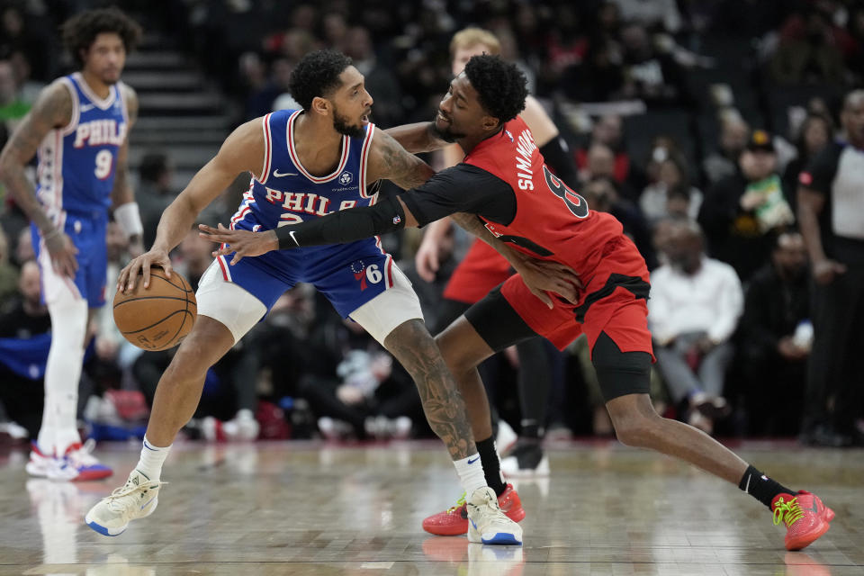 Philadelphia 76ers guard Cameron Payne (22) dribbles the ball as he keeps Toronto Raptors guard Kobi Simmons (8) at bay during the first half of an NBA basketball game Sunday, March 31, 2024, in Toronto. (Frank Gunn/The Canadian Press via AP)