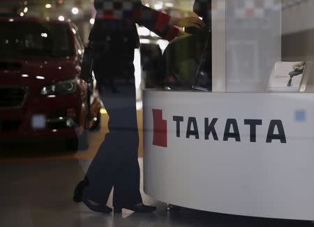 A woman stands next to a logo of Takata Corp at a showroom for vehicles in Tokyo, Japan, November 6, 2015. REUTERS/Toru Hanai