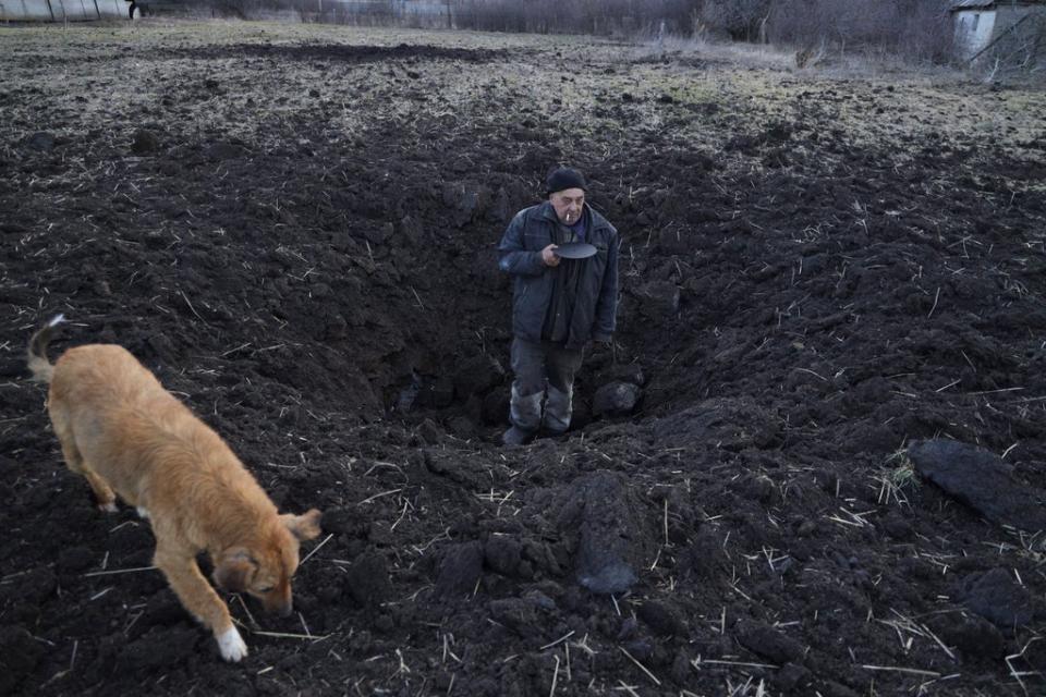 Local resident Valery shows the depth of the shell hole from the last shelling which took place in a field behind his house in a village near separatist-held city of Donetsk (EPA)