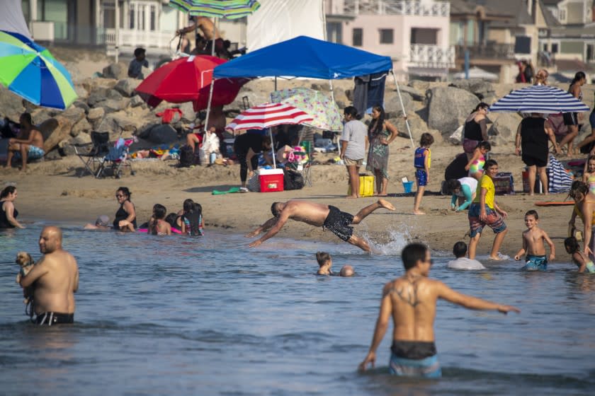 Labor Day weekend beachgoers take to the cool ocean waters in Newport Beach.