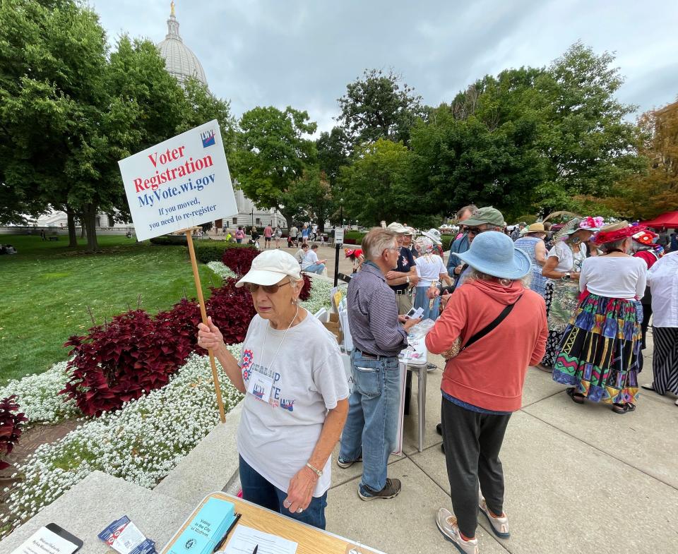 A woman encourages voter registration during the Dane County Farmer’s Market on Saturday, Aug. 26, 2023, on the Capitol Square in Madison.