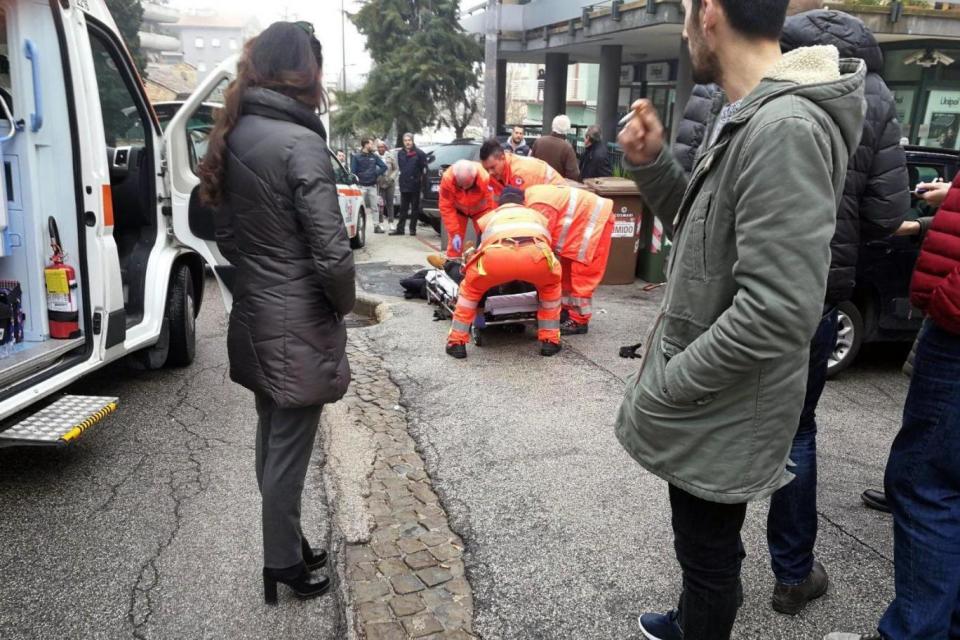 Paramedics treat an injured person that was shot from a passing vehicle in Macerata (EPA)