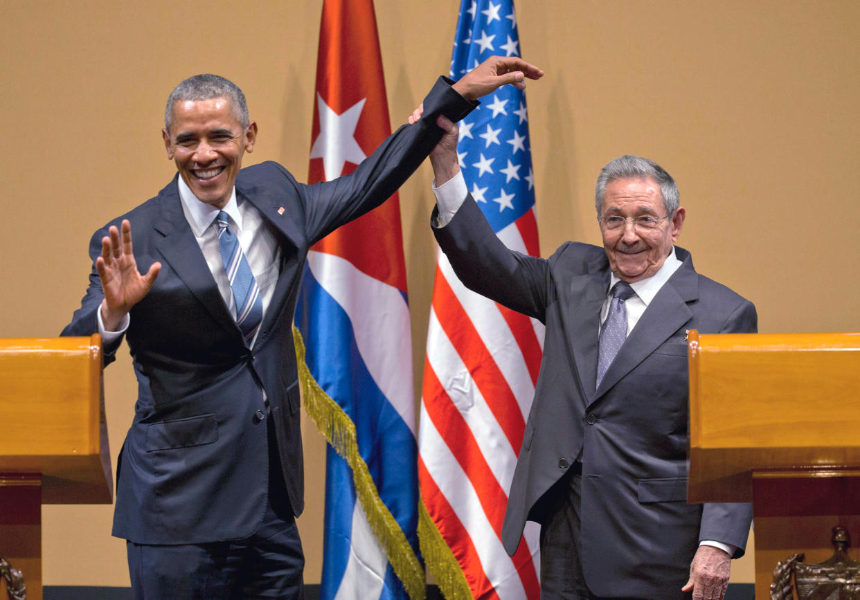 Cuban President Raul Castro lifts up the arm of President Barack Obama for what appears to be a photo-op.