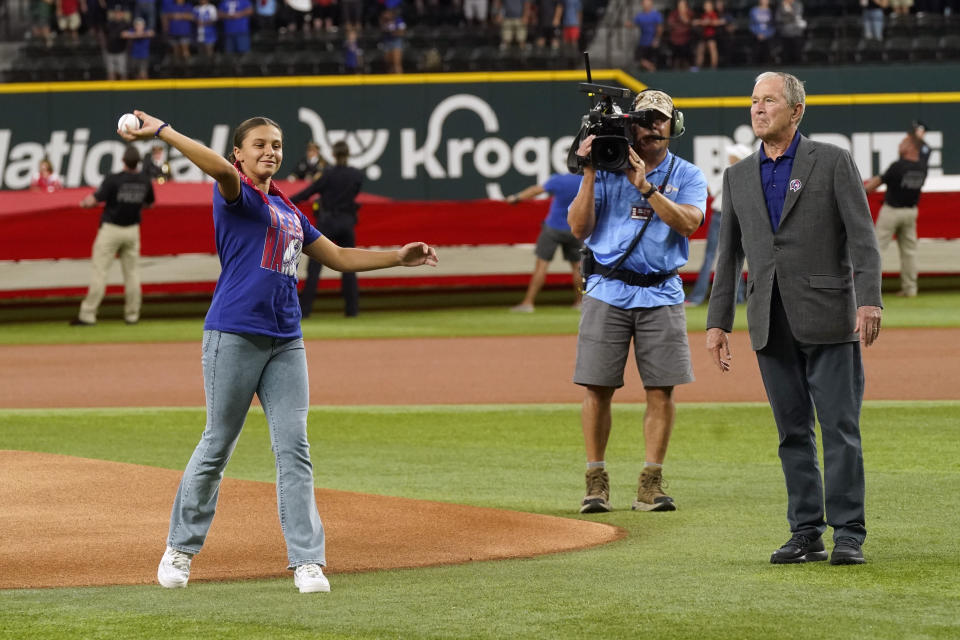 Former President George W. Bush, right, looks on as Andita Pollozani throws out the the first ceremonial pitch to recognize the 21st anniversary of Patriot Day before a baseball game between the Toronto Blue Jays and the Texas Rangers in Arlington, Texas, Sunday, Sept. 11, 2022. (AP Photo/LM Otero)