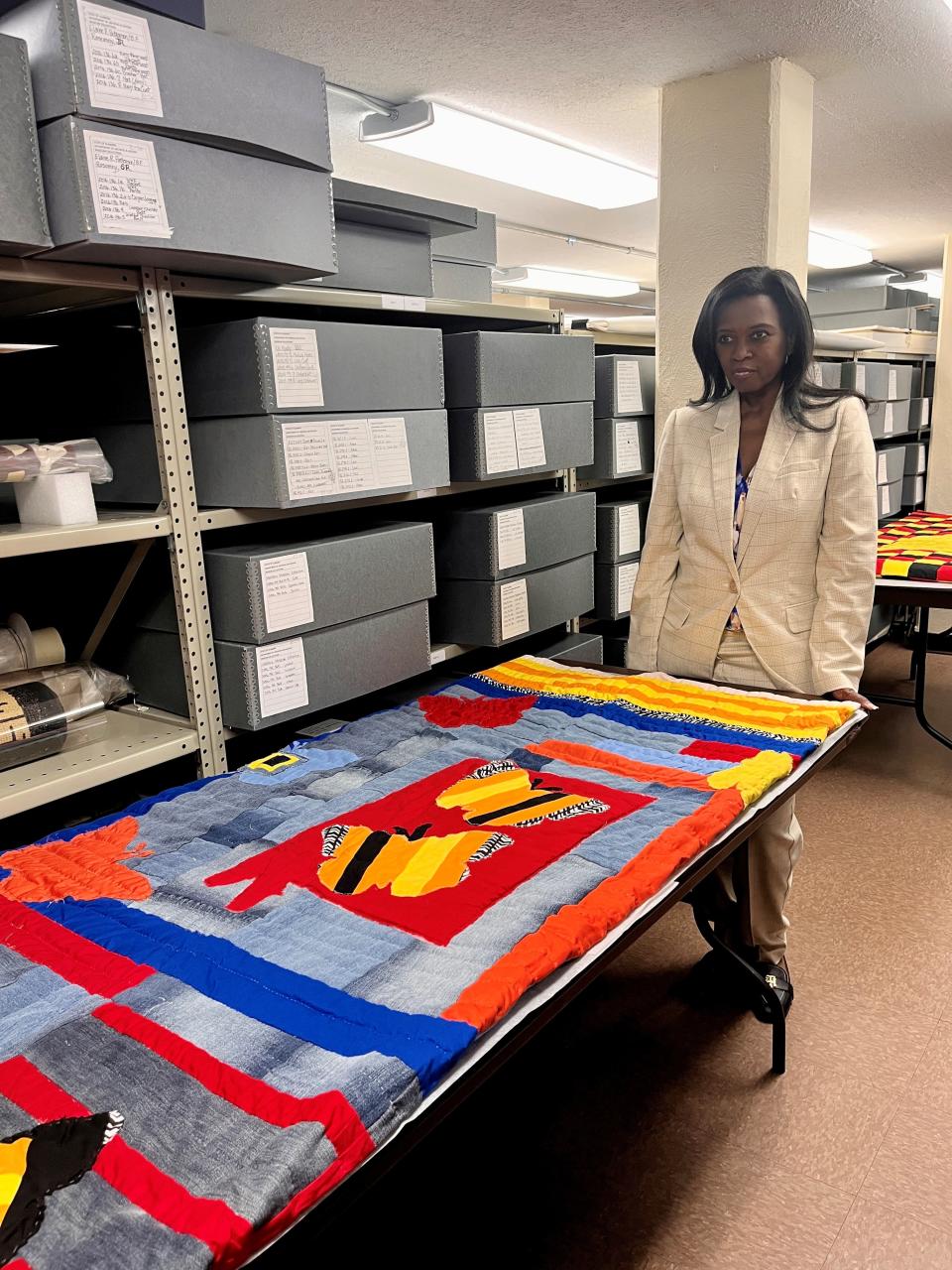 Claudia Pettway Charley stands with one of the last quilts she made with her mother. It has since been donated to the Alabama Department of Archives and History.
