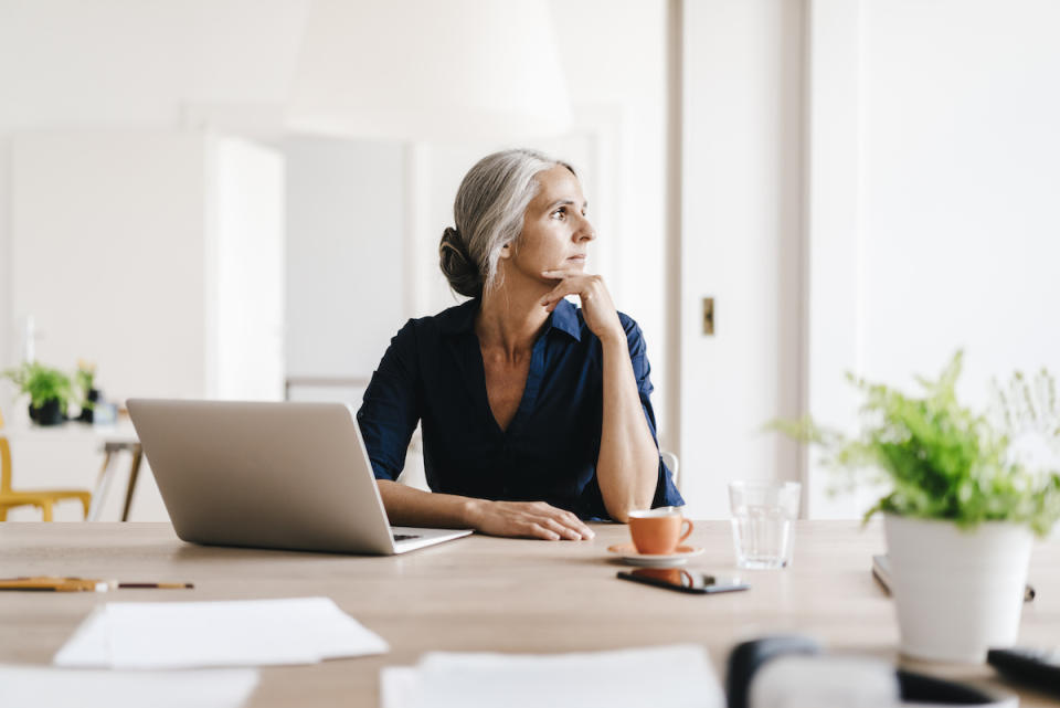 Contemplative woman sitting at desk with laptop