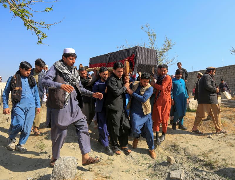 Afghan men carry the coffin of one of three female media workers who were shot and killed by unknown gunmen, in Jalalabad