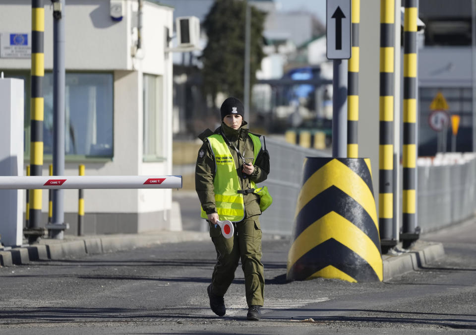 A Polish border guard gives instructions as drivers wait to cross the border from Poland into Ukraine in Medyka, Poland, on Saturday, Feb. 19, 2022. Tensions are soaring in Ukraine's east and Western leaders issue dire warnings that a wider war could be coming. But along Ukraine's border with European Union nation Poland, calm prevails. (AP Photo/Czarek Sokolowski)