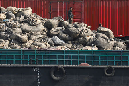 Workers stand on pile of goods at a port near North Korean town of Sinuiju, across the Yalu River from Dandong, in China's Liaoning province, April 1, 2017. REUTERS/Damir Sagolj