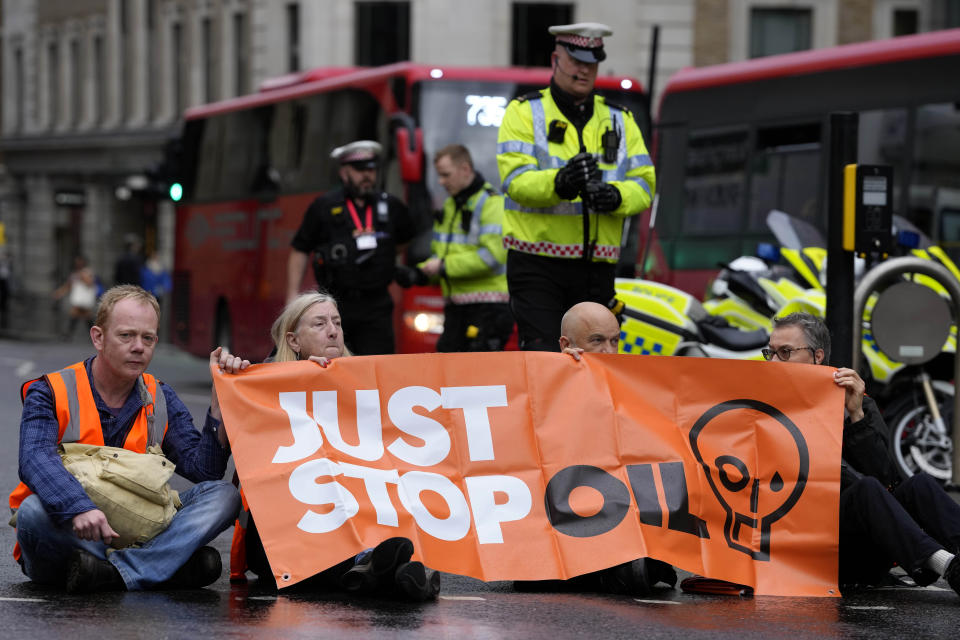 Activists from the group Just Stop Oil block a road in London, Thursday, Oct. 27, 2022 demanding to stop future gas and oil projects from going ahead. Britain is one of the world's oldest democracies, but some worry that essential rights and freedoms are under threat. They point to restrictions on protest imposed by the Conservative government that have seen environmental activists jailed peaceful but disruptive actions. (AP Photo/Kirsty Wigglesworth)