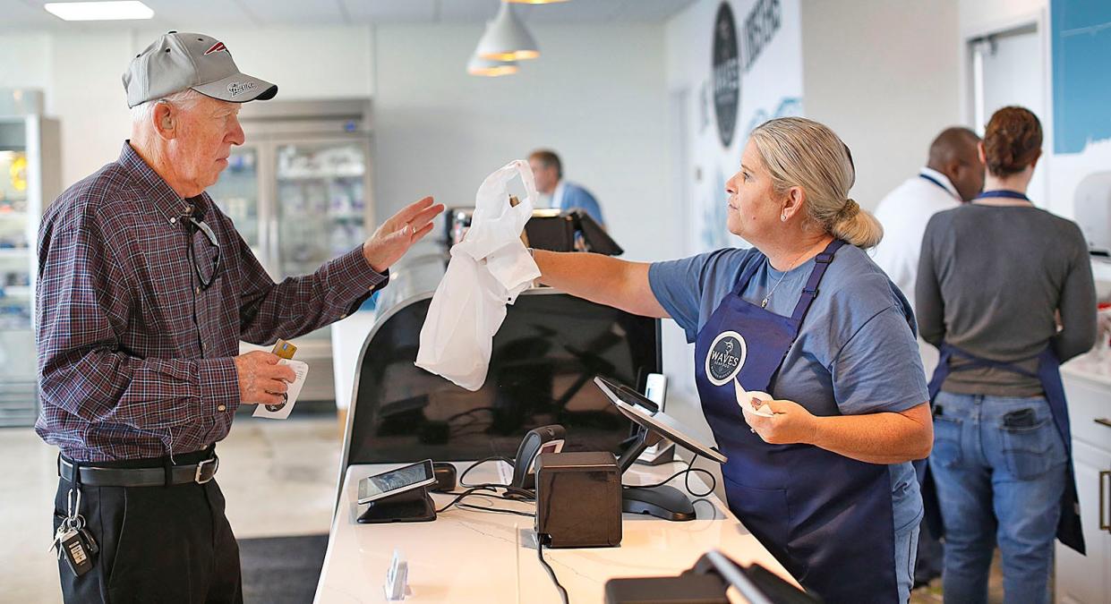 David Densmore, who has shopped at Waves Seafood in Braintree since the day it opened, buys salmon from Jennifer Briscoe at Waves.