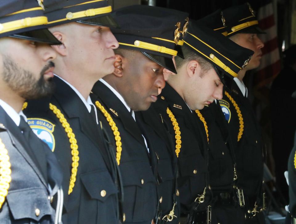 Members of the Akron Police Honor Guard bow their heads during the invocation by police Chaplain Jerry Hughes during the Akron police memorial service Wednesday at Wolter Park.