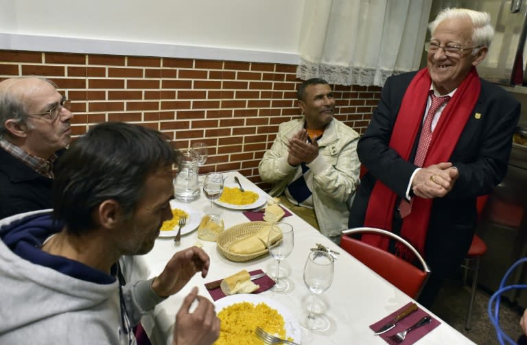 Angel Garcia (R) speaks with homeless people eating a free dinner at the Robin Hood restaurant in Madrid