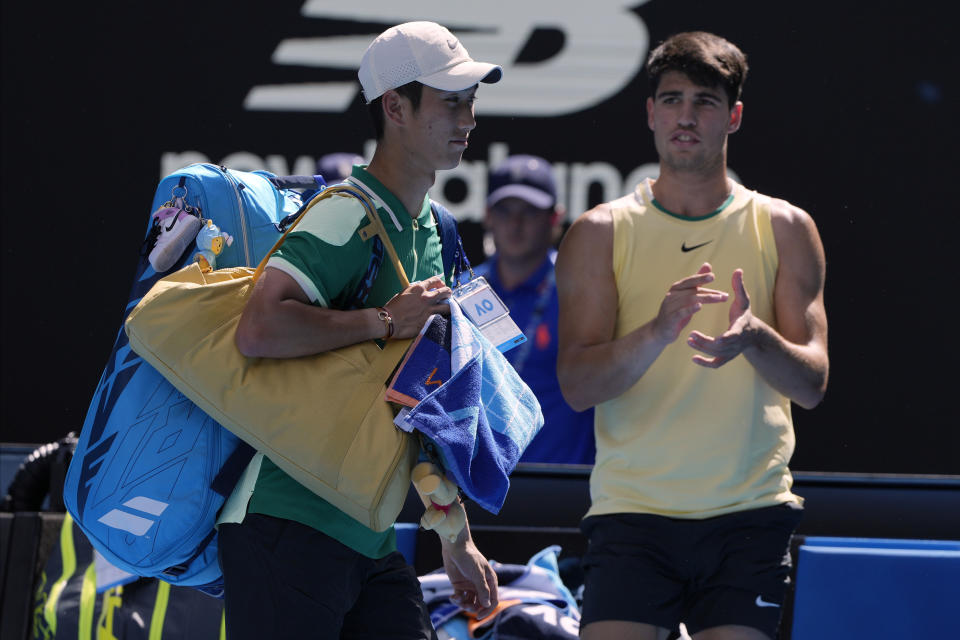 Shang Juncheng, left, of China walks from Rod Laver Arena after retiring in his third round match against Carlos Alcaraz of Spain at the Australian Open tennis championships at Melbourne Park, Melbourne, Australia, Saturday, Jan. 20, 2024. (AP Photo/Andy Wong)