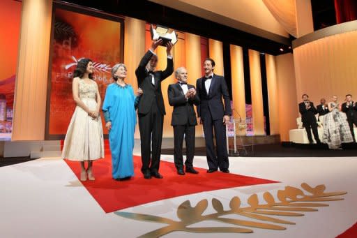 Austrian director Michael Haneke (C) raises his trophy as he poses on stage with French actors Audrey Tautou (L), Emmanuelle Riva (2nd L), Jean-Louis Trintignant and US actor Adrien Brody after being awarded with the Palme d'Or for his film "Amour" during the closing ceremony of the 65th Cannes film festival