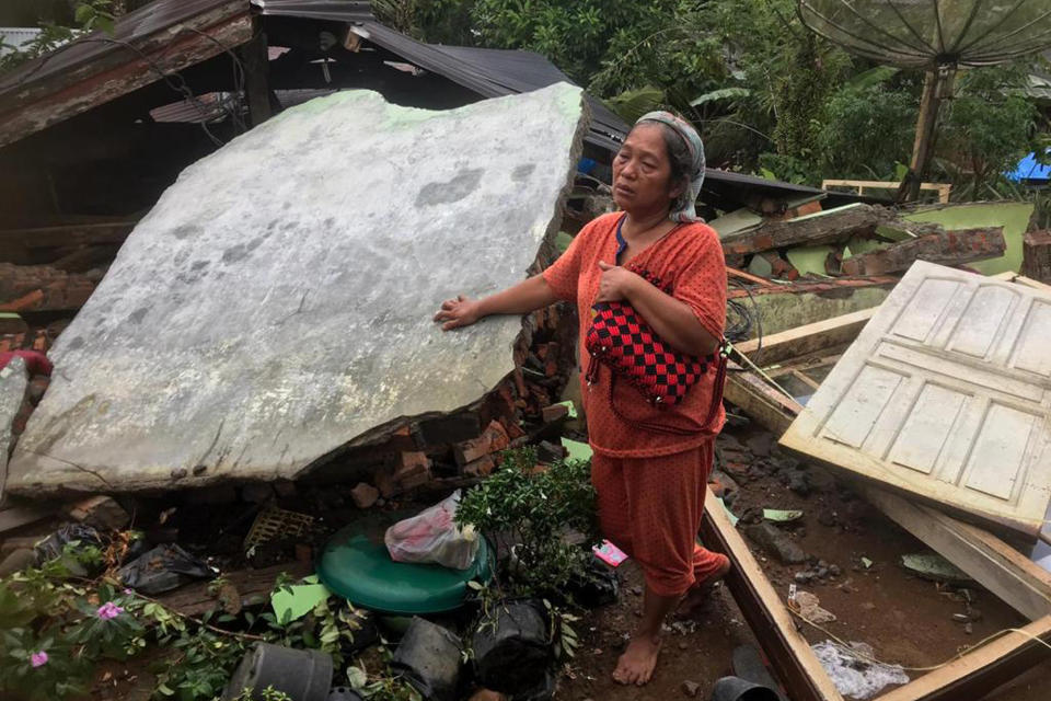 A woman reacts as she stands at the ruin of her house following an earthquake in West Pasaman district, West Sumatra, Indonesia, Friday, Feb. 25, 2022. The strong and shallow earthquake rocked Sumatra on Friday, panicking people on the island and neighboring Malaysia and Singapore. (AP Photo/Rahma Nurjana)