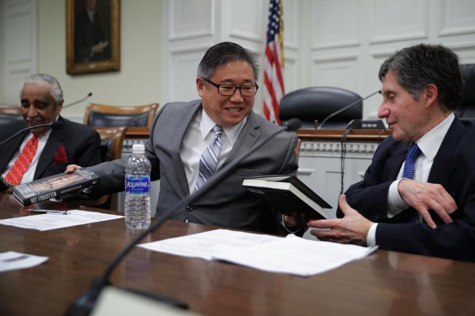 Kenneth Bae (centre) gives copies of his new book ‘Not Forgotten’, to representative Charles Rangel (left) and Ambassador Joseph DeTrani (right) (Getty Images)