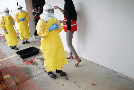 Kwan Keu Lai (C), a doctor with Beth Israel Deaconess Medical Center, waits as she receives guidance from Centers for Disease Control and Prevention (CDC) instructor Rupa Narra (R) along with other health care workers, in preparation for the response to the current Ebola outbreak, during a CDC safety training course in Anniston, Alabama, October 6, 2014. REUTERS/Tami Chappell