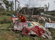 A woman spreads quilts and sheets for drying after salvaging them from the rubble of her damaged house in the aftermath of Cyclone Amphan, in South 24 Parganas district