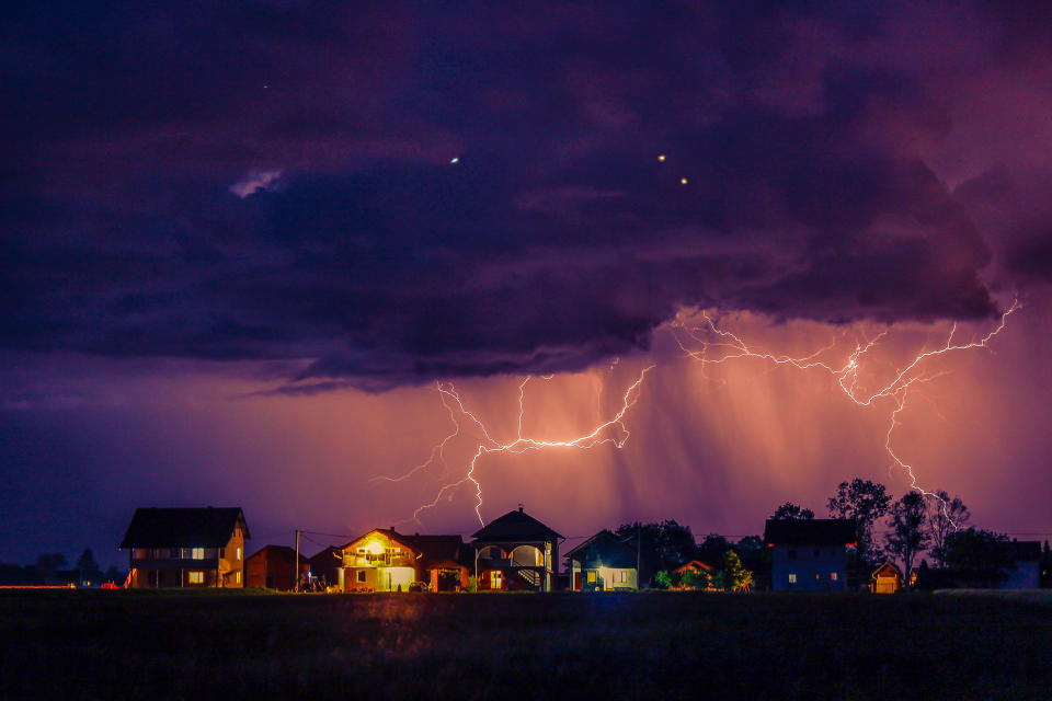 Lightning strikes over a row of suburban houses.