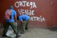 Paramilitaries clean the floor in front of a grafitti reading "Ortega homeland seller" at Monimbo neighborhood in Masaya, Nicaragua, on July 18, 2018, following clashes with anti-government demonstrators
