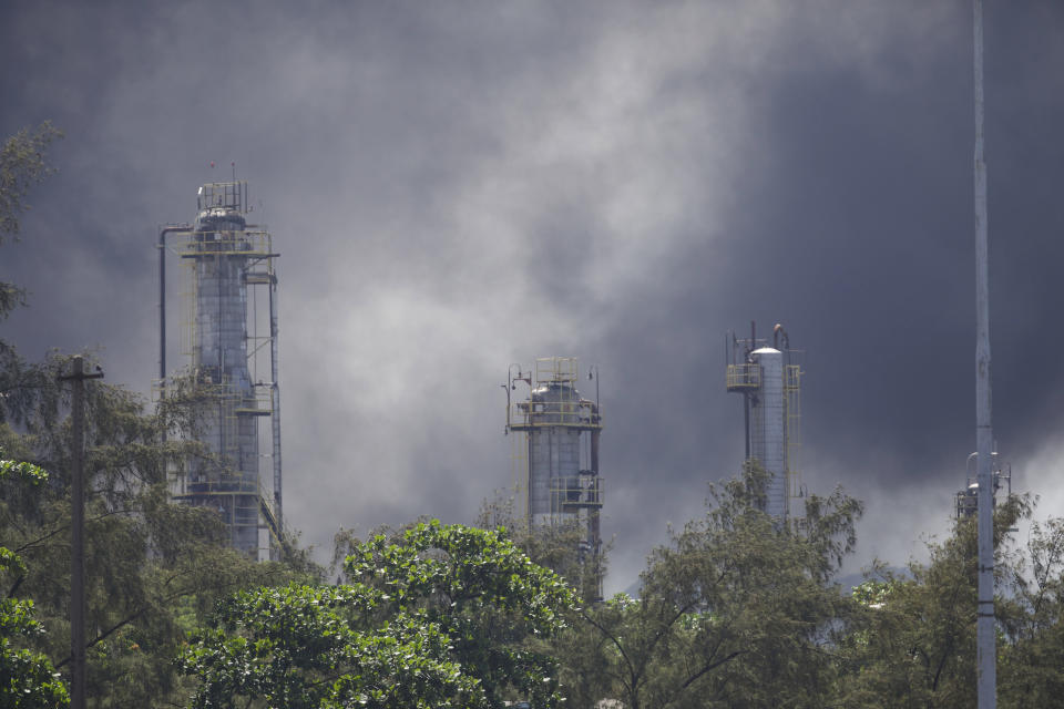 Smoke rises from the Manguinhos refinery, in Rio de Janeiro, Brazil, Monday, Dec. 17, 2018. Firefighters in Brazil say a fire has been brought under control at the large refinery. The Rio de Janeiro fire department said the conflagration began when a tanker truck at the Manguinhos refinery exploded Monday afternoon. At least six other tankers were destroyed by the flames. (AP Photo/Silvia Izquierdo)