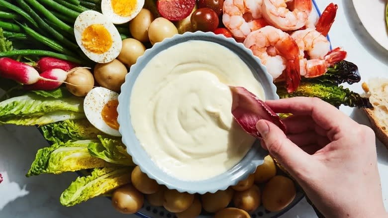 hand dipping vegetable into aioli